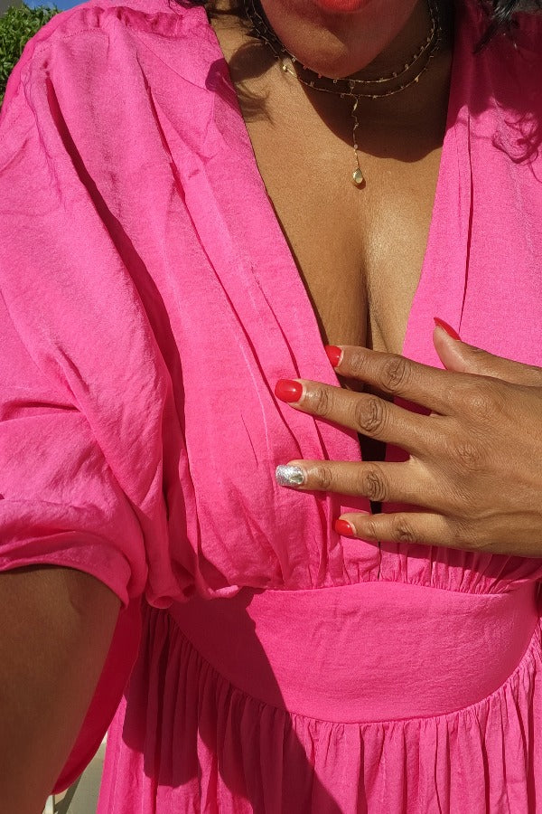 a woman in a pink dress holding a pink cell phone 