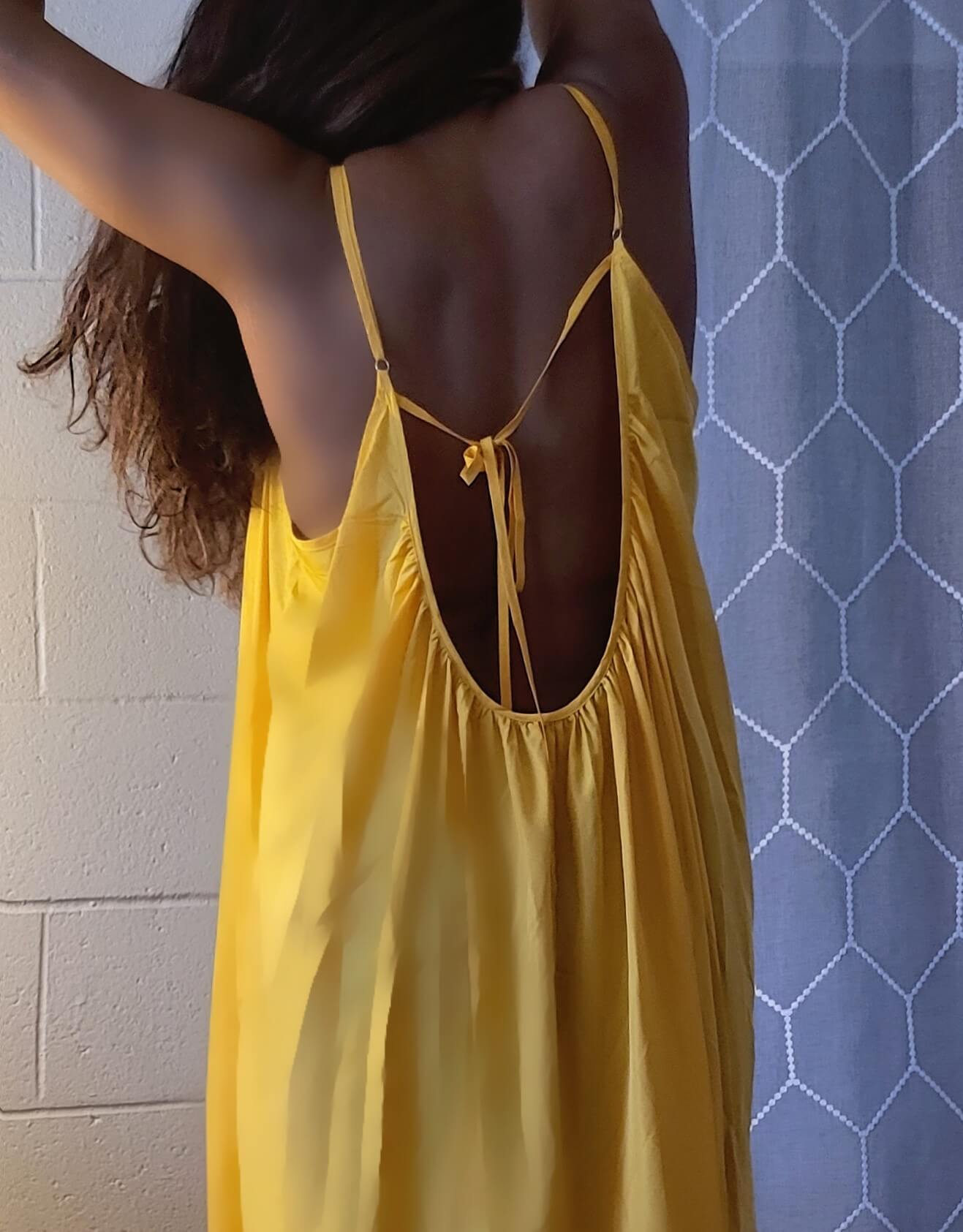 a woman in a yellow dress holding a cell phone 