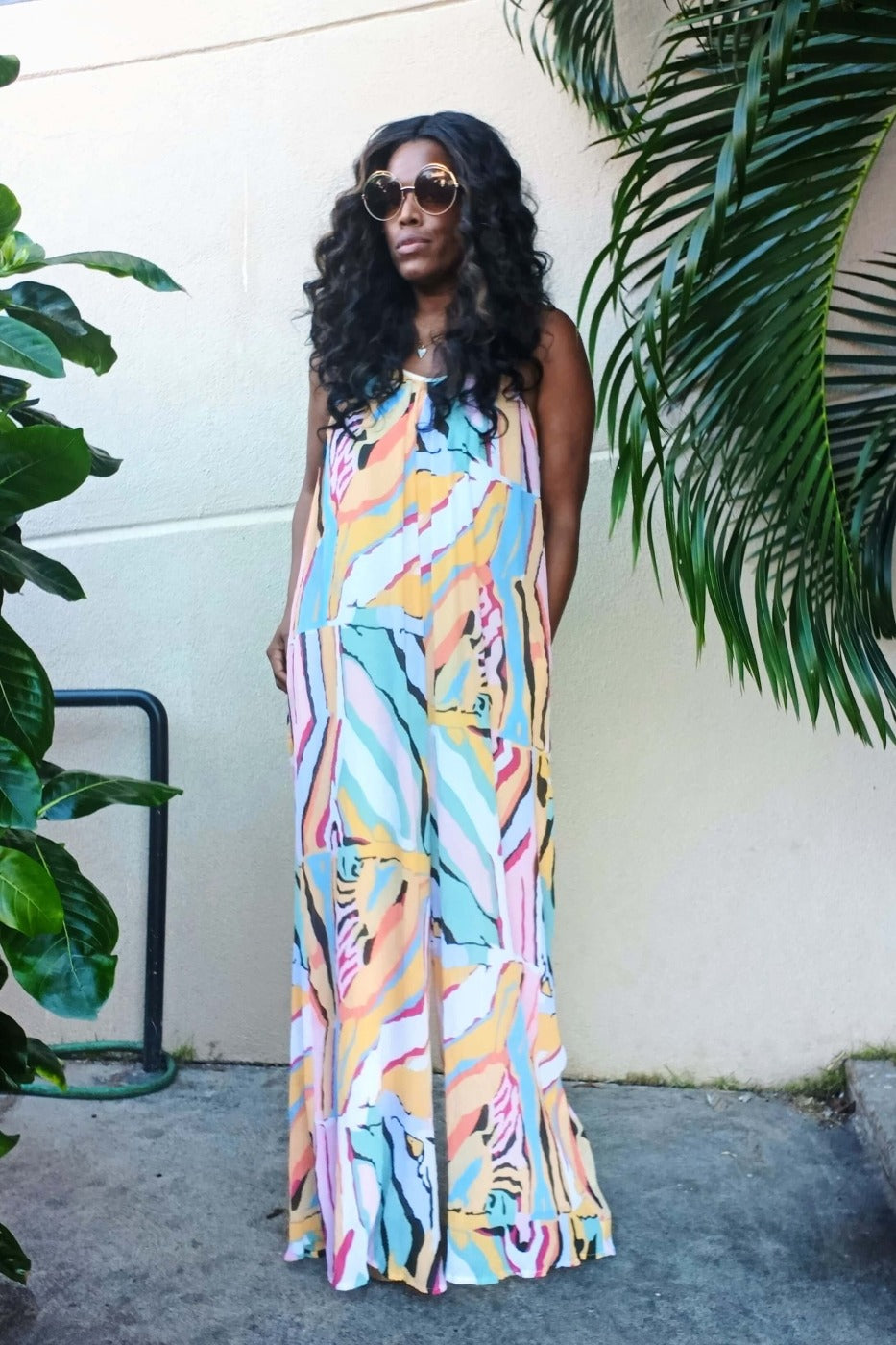 a woman in a dress standing next to a palm tree