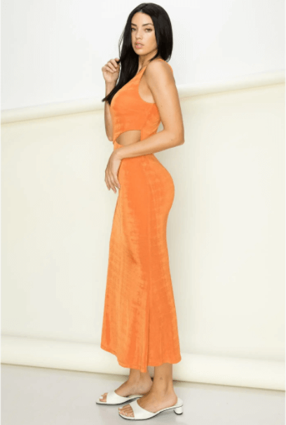 a woman in a orange dress standing on a skateboard